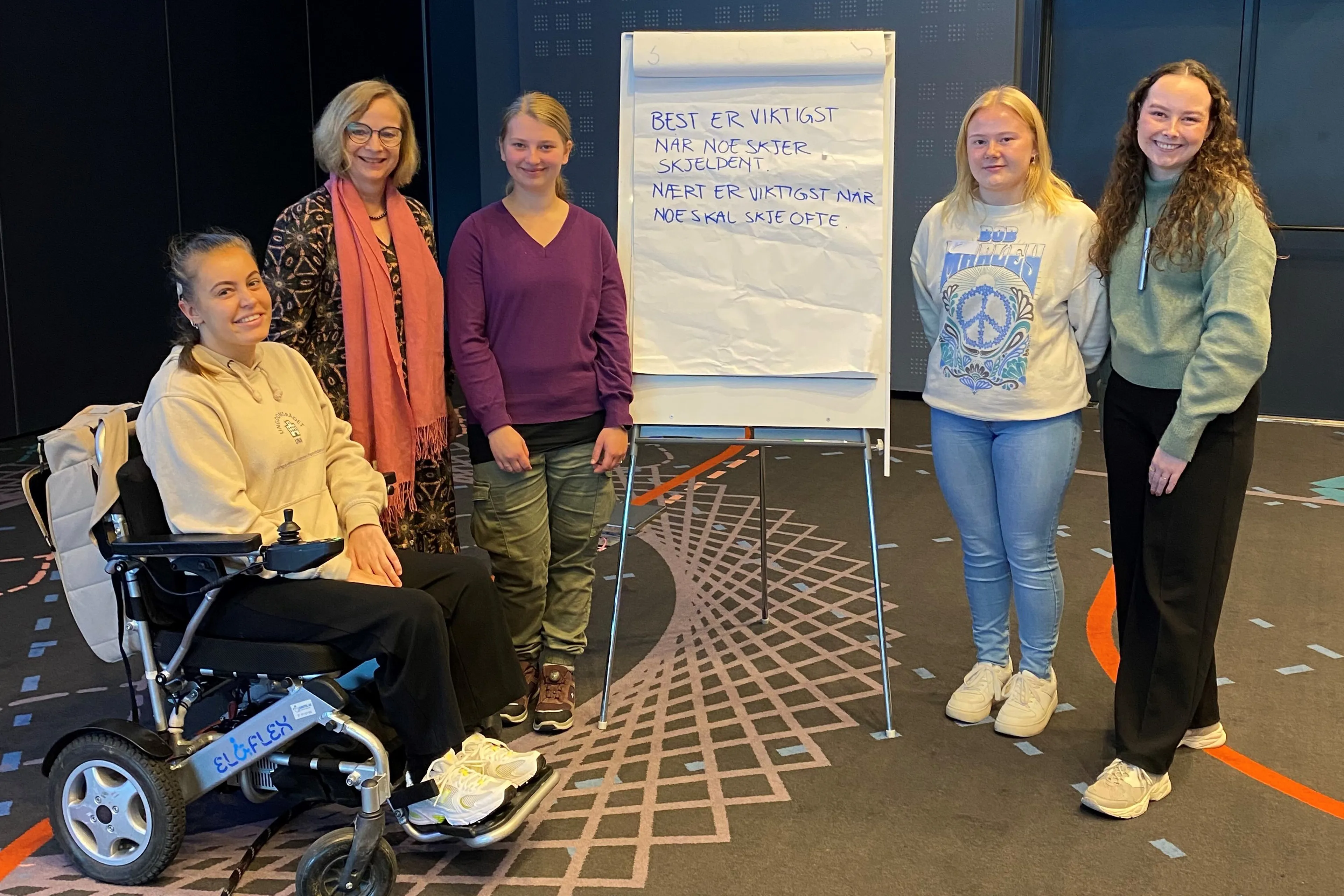 En gruppe kvinner som står ved siden av en person i rullestol