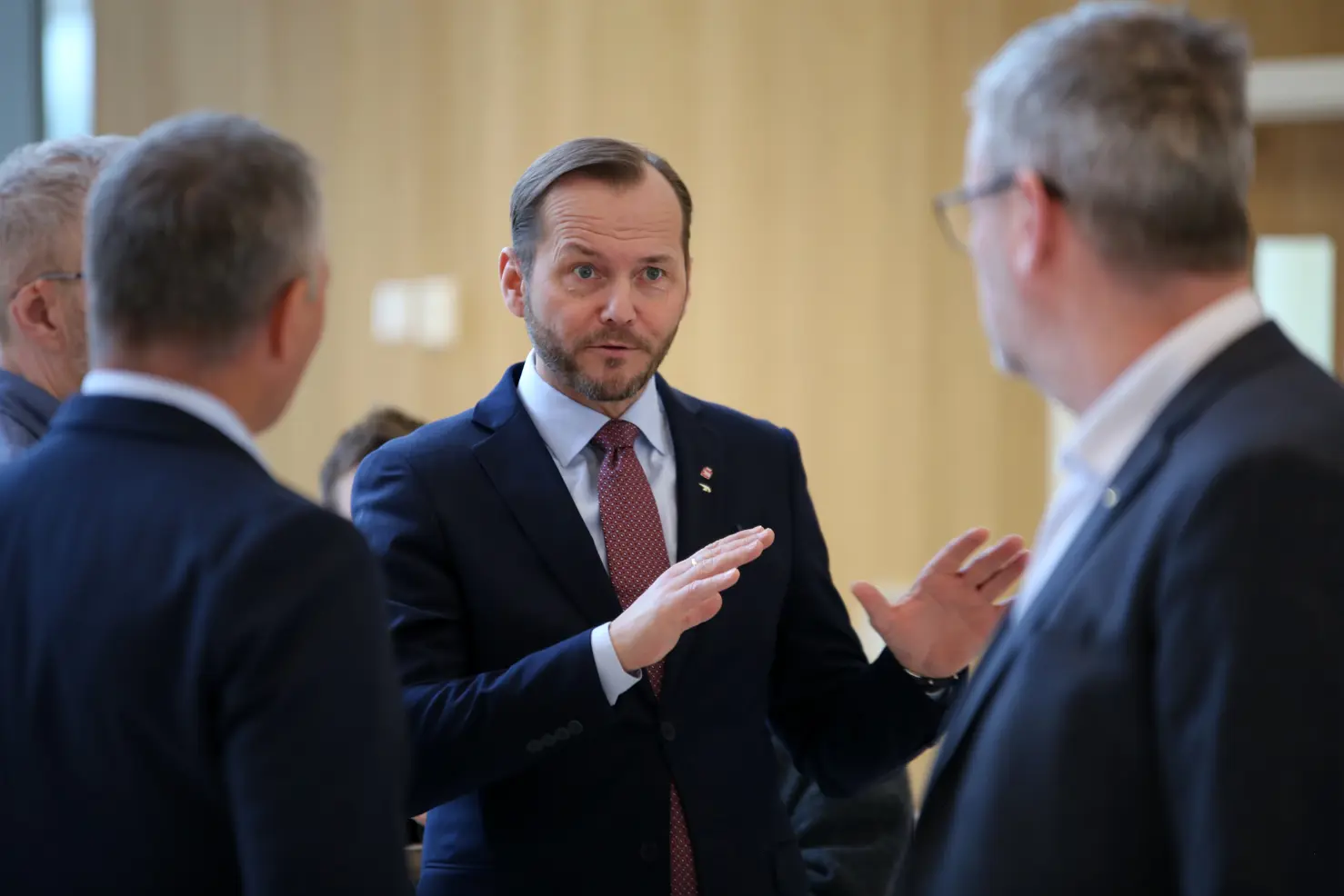En mann i dress som snakker med en gruppe menn