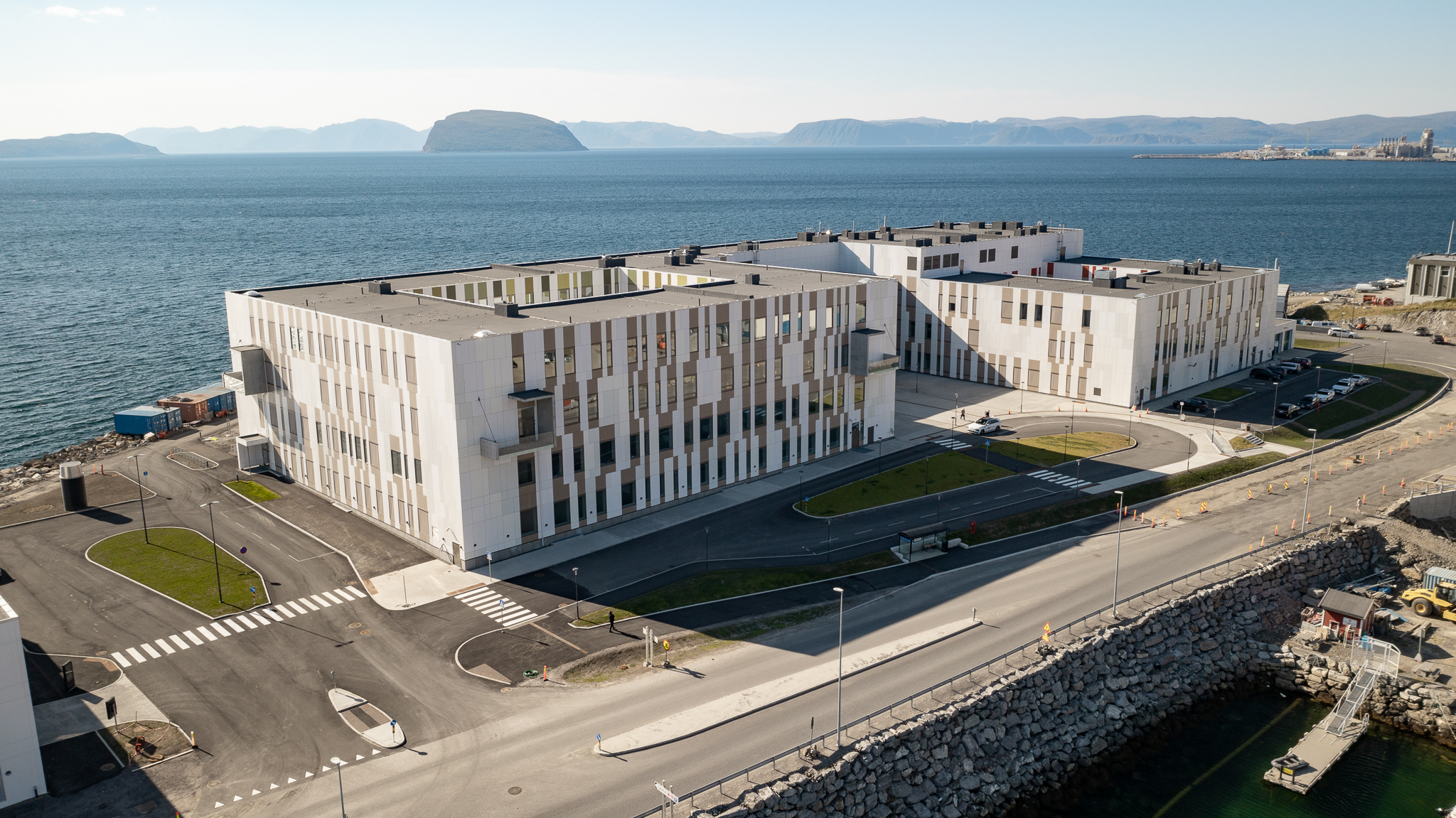 Hammerfest sykehus sett fra dronevinkel som viser bygget foran havet og parkeringsplass i front