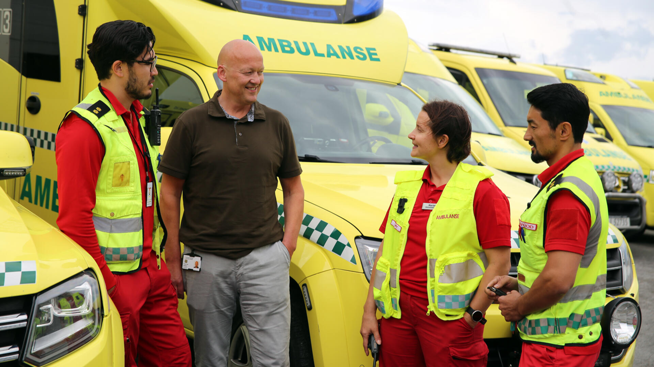 En gruppe ansatte som står ved siden av flere ambulanser