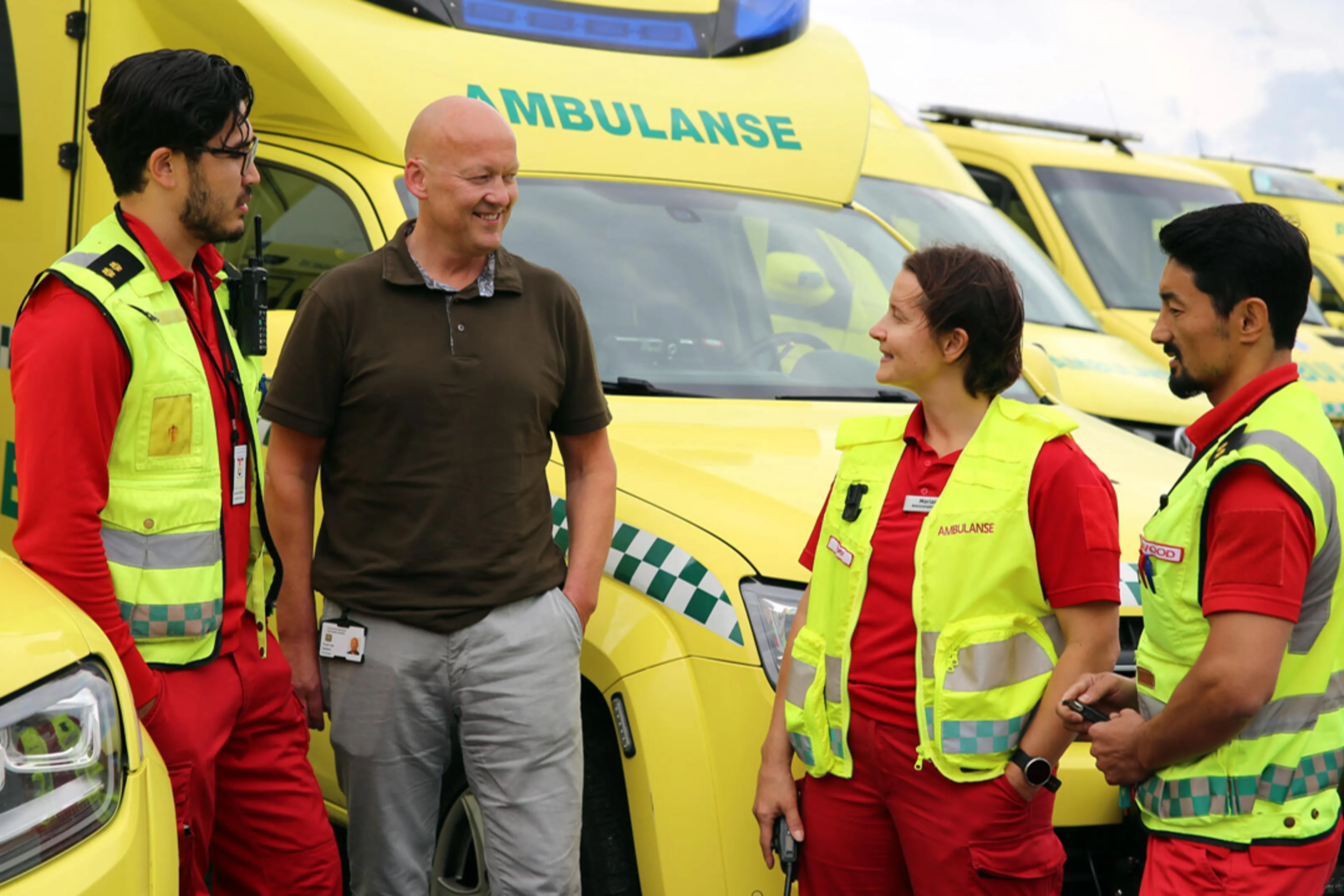 En gruppe ansatte som står ved siden av flere ambulanser