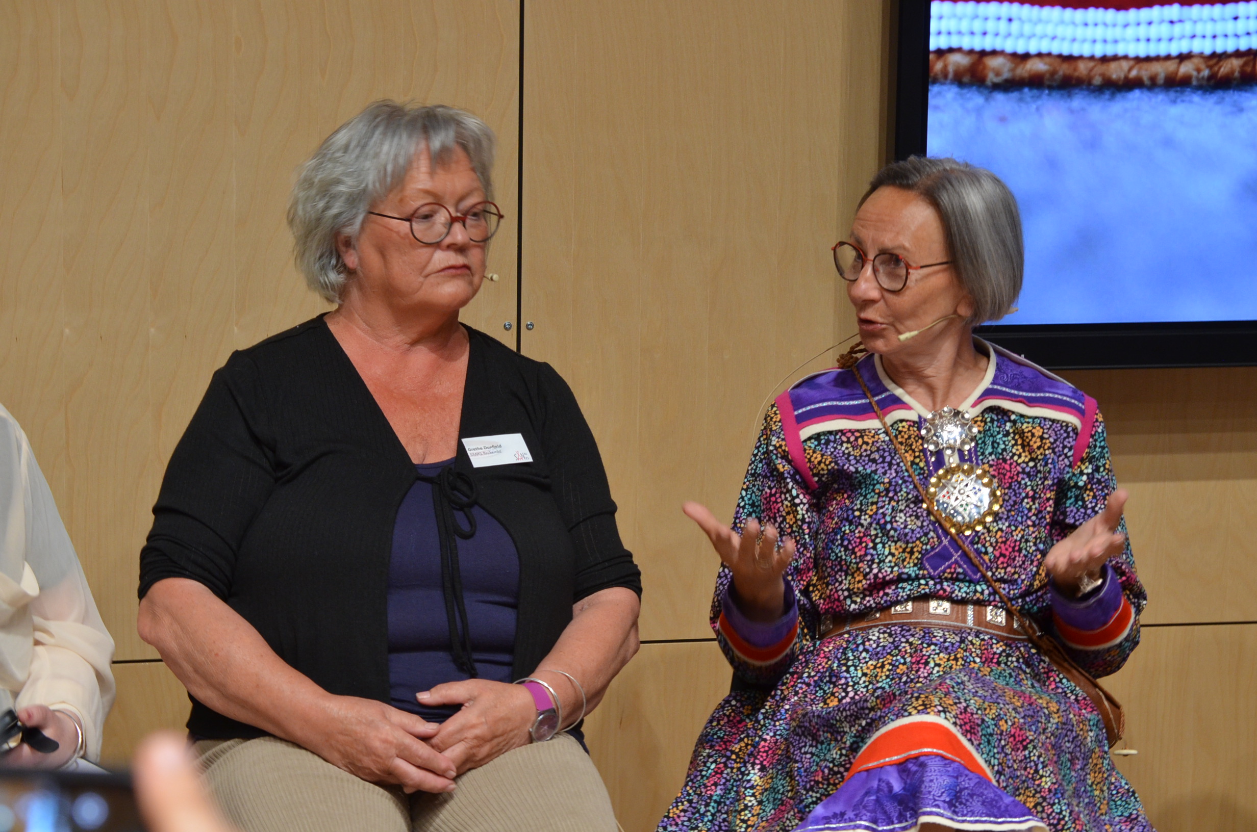 Et par kvinner som sitter ved siden av hverandre og ser inn i kameraet