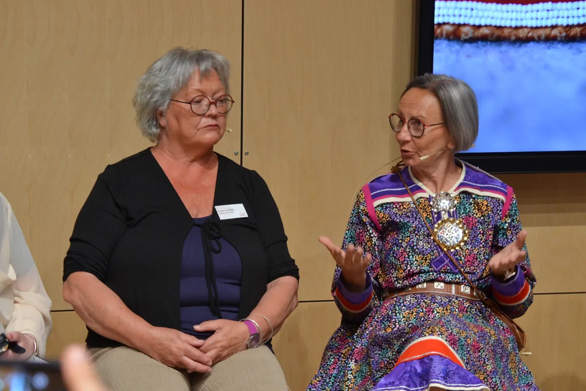 Et par kvinner som sitter ved siden av hverandre og ser inn i kameraet