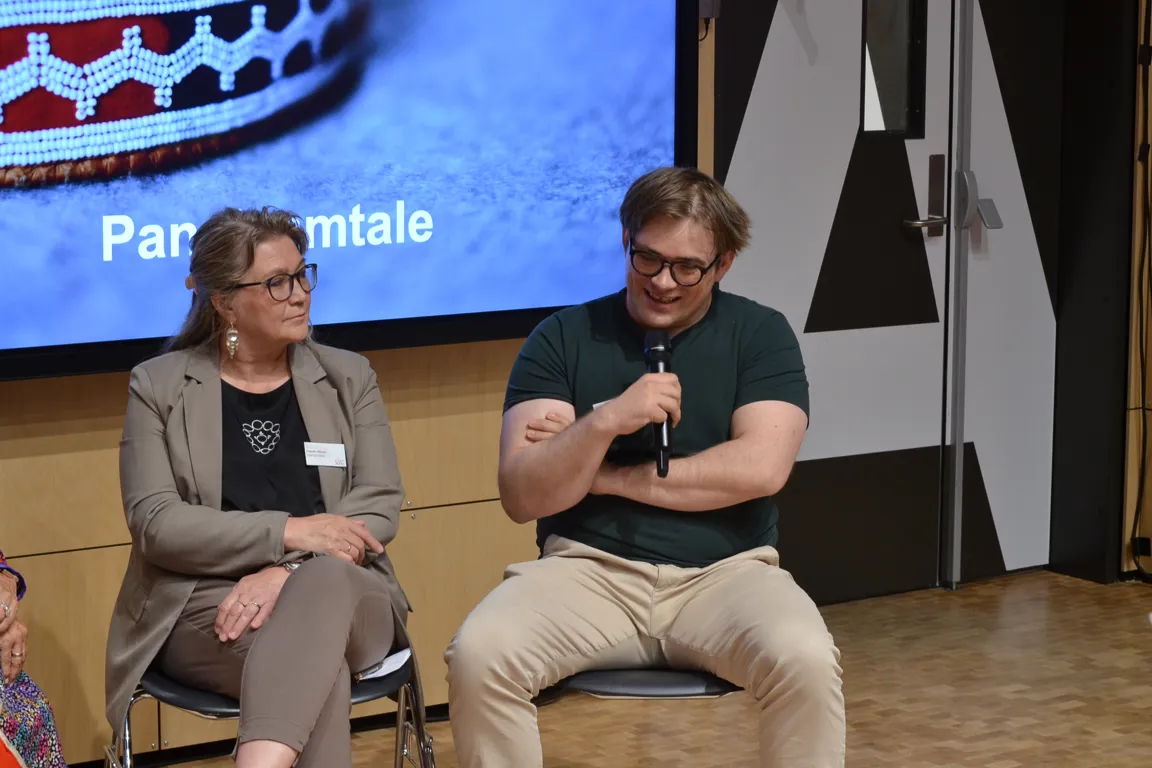 En mann og en kvinne som sitter på en scene med en mikrofon