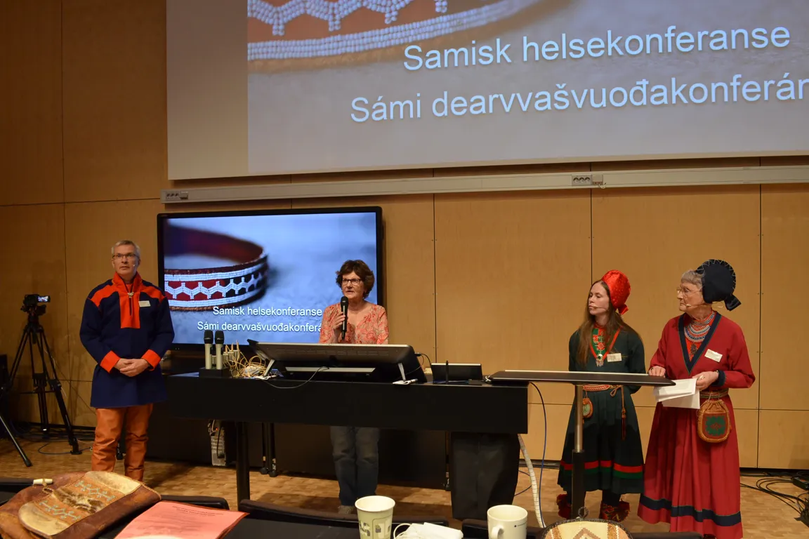 En gruppe mennesker som står foran en scene med en skjerm