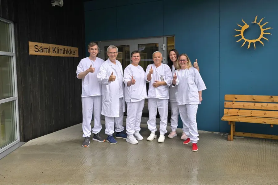 En gruppe mennesker i hvite labfrakker poserer for et bilde