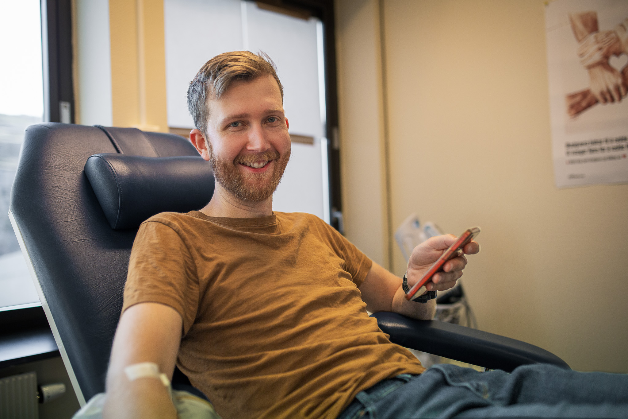 En mann som sitter i en stol og smiler til kameraet