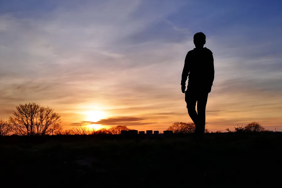 En person som går foran en solnedgang