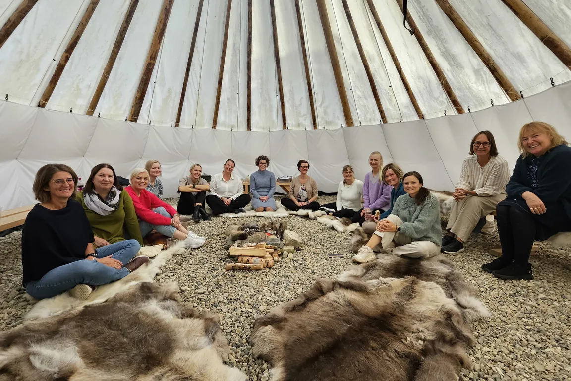 En gruppe mennesker som sitter på en haug med høy