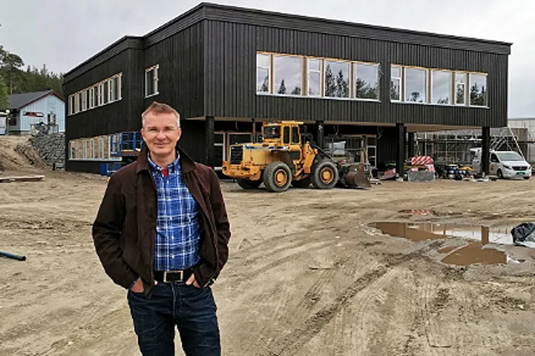 En mann som står foran en bygning med en traktor i bakgrunnen