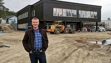En mann som står foran en bygning med en traktor i bakgrunnen