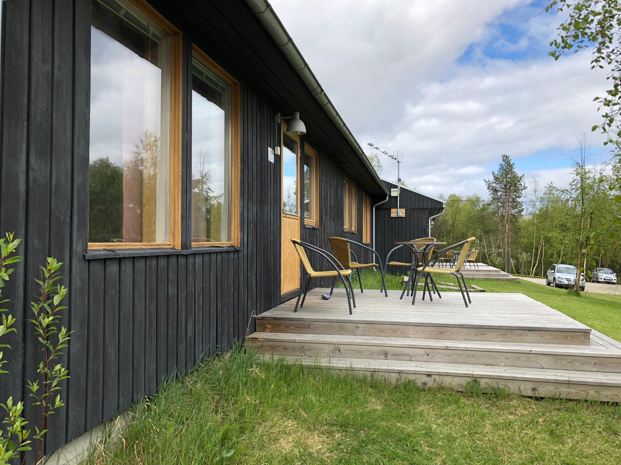 Et tredekk med stoler og et bord på det ved siden av et hus