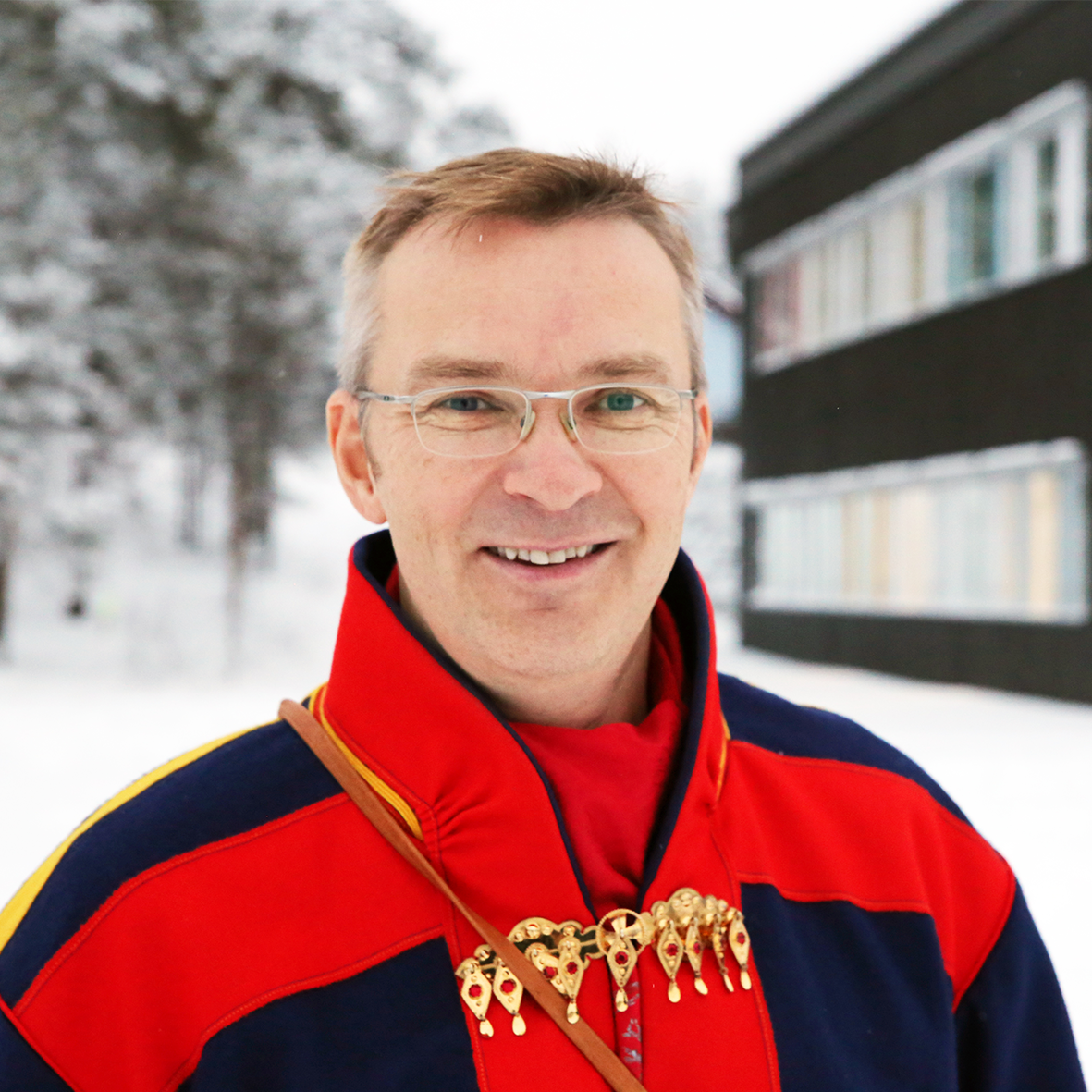 En mann iført rød og blå kappe og briller