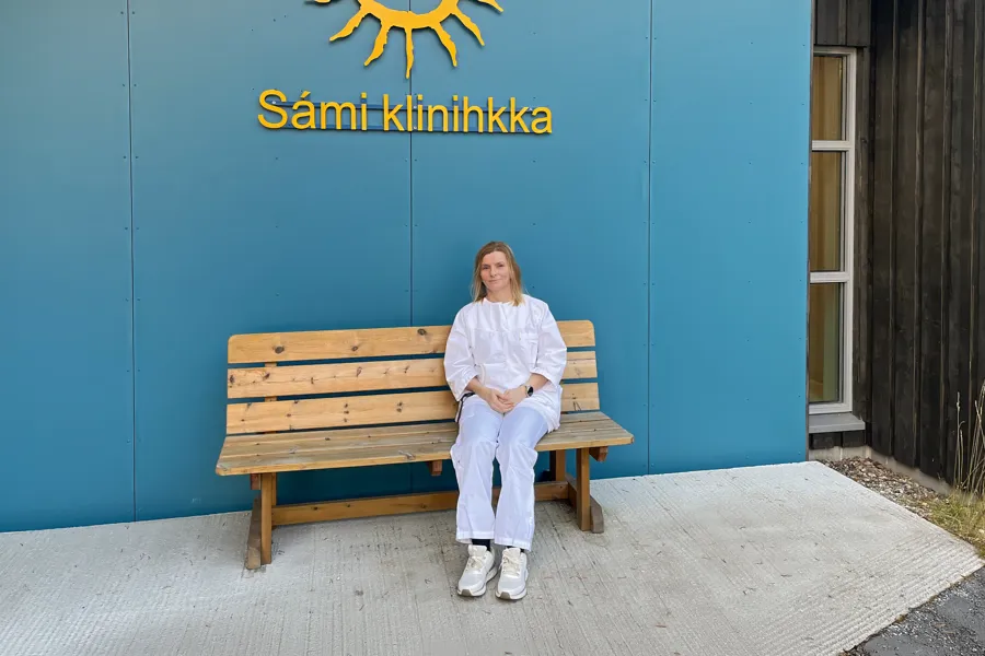 Nordsamisk tolk sitter på en benk utenfor Sámi klinihkka.