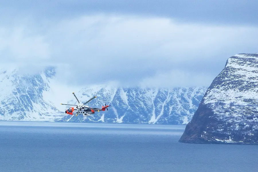 Et helikopter som flyr over et snødekt fjell