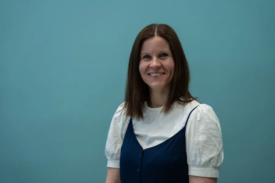 En person som smiler foran en blå vegg