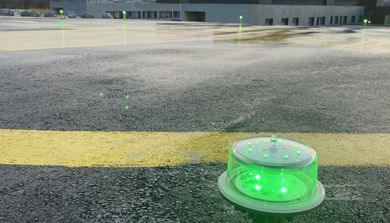 En grønn plastkopp på en gul stolpe foran en bygning